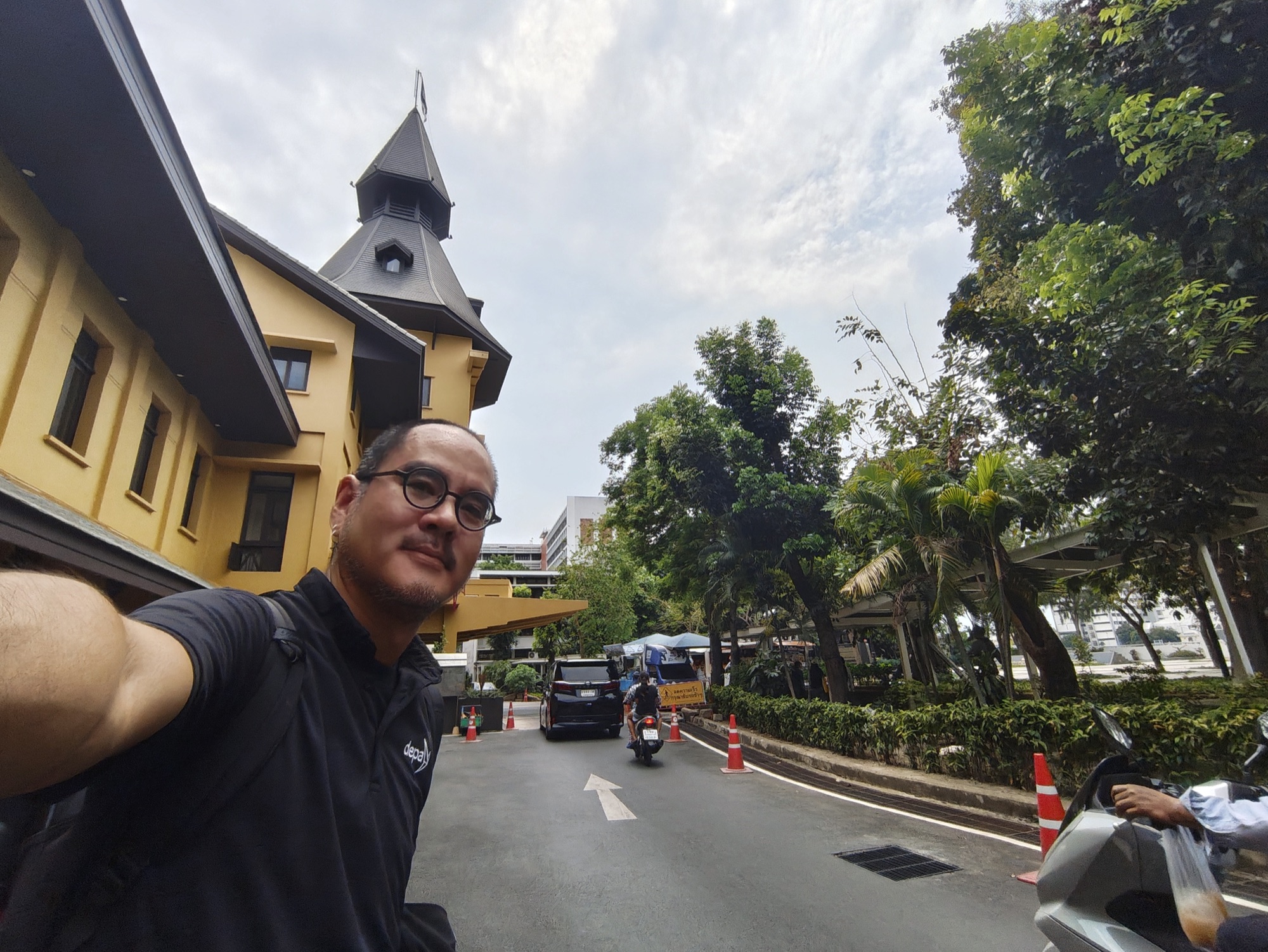 Dr Non standing outside a clock tower building at Thammasat University in Bangkok's old town